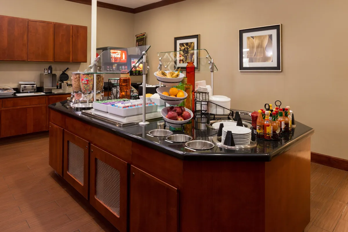 A bright and welcoming breakfast bar displaying a variety of fresh fruit, a well-stocked coffee station, and ample counter space for guests to enjoy a complimentary breakfast or morning coffee.